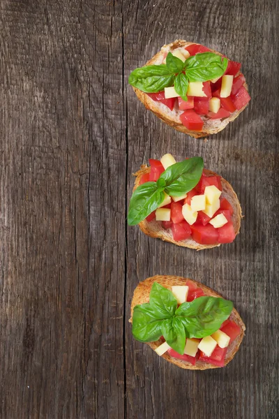 Bruschetta s rajčaty, sýrem a bazalkou — Stock fotografie