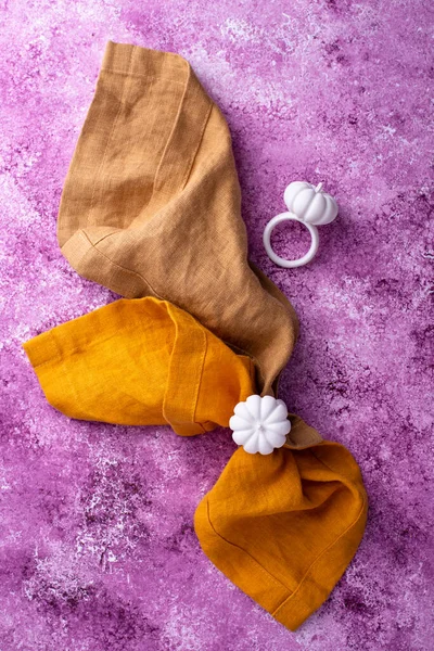 Linen tablecloth with napkin ring on lilac concrete background