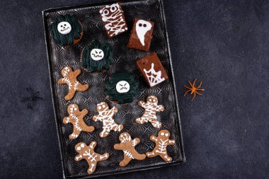 Korkunç Cadılar Bayramı tatlıları seti. Mumya kurabiyeleri, canavar kekler ve hayalet brovniler.