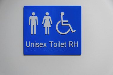 Beyaz duvarda Braille yazısıyla Unisex ve Engelli tuvalet tabelası