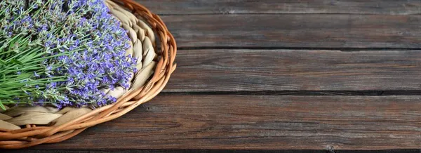 Свежие фиолетовые цветы лаванды на плетеном блюде на деревянном столе. — стоковое фото