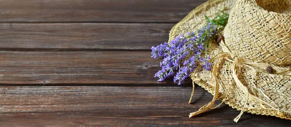 Плетеная шляпа с букетом фиолетовых цветов лаванды на деревянном столе. — стоковое фото