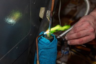 Klima teknisyeni ekipmanları onarmak için bir meşale kullanıyor.