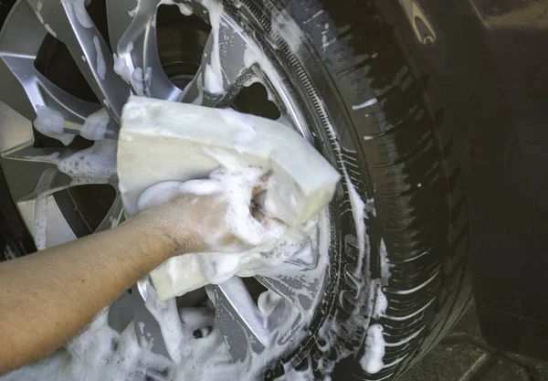Adam arabayı köpükle yıkıyor.
