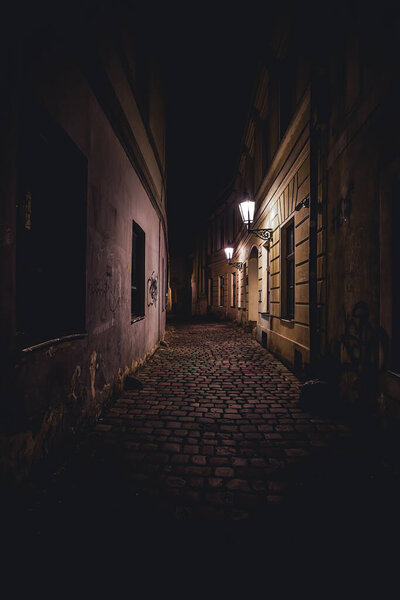 View of a dark and illuminated cobblestone street in the old town of prague at night 2021