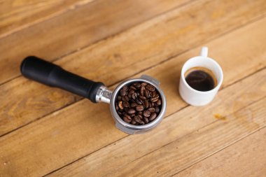 En iyi kahve çekirdekleri dipsiz filtrede, siyah kahve fincanı tahtada, seçici odaklı. Kahve çekirdekleri dipsiz bir filtrede, ahşap bir masada..