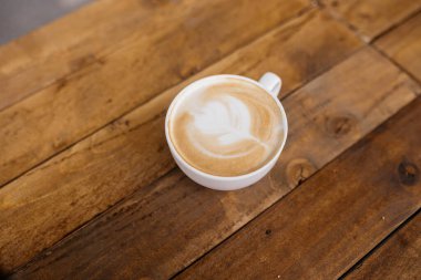 Kahve dükkanındaki ahşap sehpanın üzerinde kahve tutan kadın. Bardakta kahve..