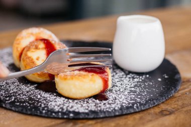 Bardaklı peynirli gözleme, ev yapımı Ukrayna usulü ve Rus kibritleri, seçici odaklanma. Tabaktaki peynirli kekler. Peynirli krep ya da çilek reçelli peynirli kek..