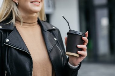 Girl holding a cardboard cup. Paper coffee cup in a woman hand on store background. Hot drink. Hand holding paper cup of coffee. Paper coffee cup.