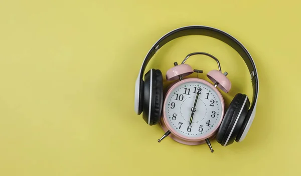 粉色老式闹钟的顶部视图或平面布局显示了6点钟的封面 带有黄色背景的耳机 时间听音乐概念或播客背景 — 图库照片