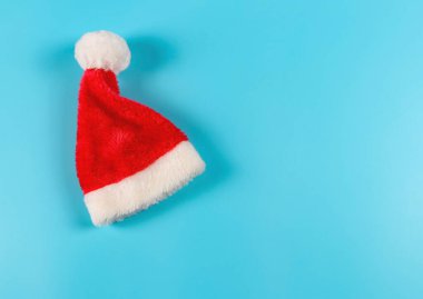 Mavi arka planda parlak kırmızı Noel Baba şapkası var. Noel arkaplanı.