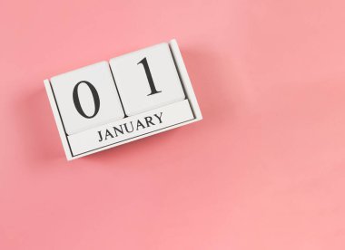 Ahşap takvimin en üst görüntüsü 01 Ocak 'ta pembe arka planda. Yılın ilk günü..
