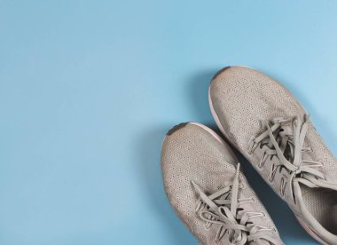 Üst görünümü veya düz gri spor ayakkabıları mavi arka planda fotokopi alanı ile. Spor ve kilo verme konsepti.