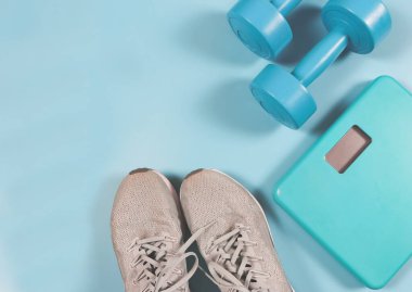 Üst ya da düz gri spor ayakkabılar, dijital ağırlık ölçeği, mavi arka planda mavi halterler. sağlıklı yaşam tarzı ve kilo verme kavramı.