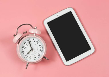 Pembe alarmlı saatin üst görünümü veya düz yatağı ve pembe arkaplanda kopyalama alanı için boş ekran dijital tableti.