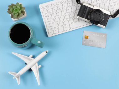 Üst ya da düz bilgisayar klavyesi, mavi kahve fincanı, uçak modeli, kredi kartı ve mavi arkaplanlı sulu bitki saksısı. İş ve Seyahat kavramı.