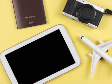 Üst görünüm veya düz pasaport, kamera ve uçak modeli ve sarı zemin üzerinde boş siyah ekran ile dijital tablet.
