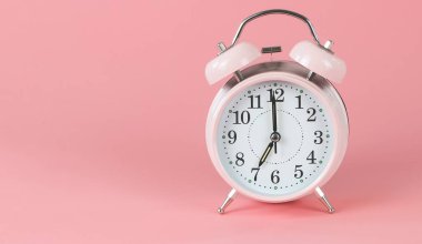 Pembe antika alarm saatinin ön görüntüsü saat 7: 00 'de fotokopi alanı ile birlikte pembe arkaplanda.