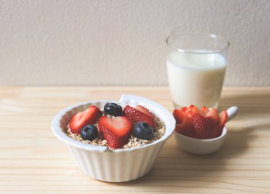 Kahvaltıda yulaf, tahıl gevreği, taze yaban mersini, çilek ve bir bardak süt. Sağlıklı kahvaltı kavramı.