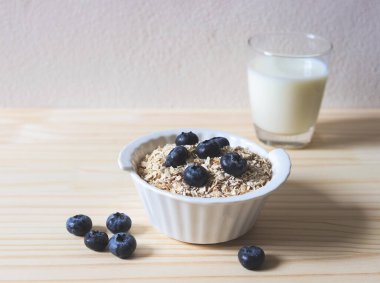 Kahvaltıda yulaf, tahıl gevreği, taze yaban mersini ve bir bardak süt. Sağlıklı kahvaltı kavramı.
