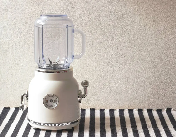 Front view of empty white vintage blender or smoothie maker  on  black and white stripe table cloth and white wall.