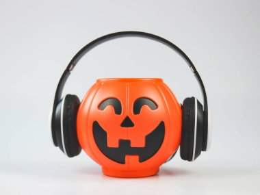 Kulaklıklı plastik cadılar bayramı balkabağı örtüsünün ön görüntüsü. Beyaz arka planda, kopyalama alanı ile izole edilmiş. Cadılar Bayramı müziği veya podcast.