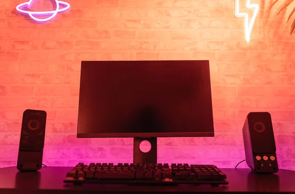 Computer gamer workspace with black screen monitor with neons and colorful lights. Gamer Rig.