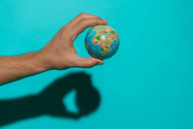 Metin için kopyalama alanı olan renkli mavi arkaplan ile dünyayı tutan top.