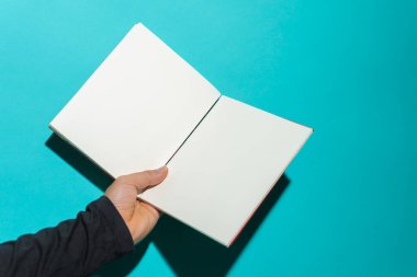 Mavi arkaplan önünde temiz beyaz sayfaları olan, metin için kopyalama alanı olan açık bir kitap..