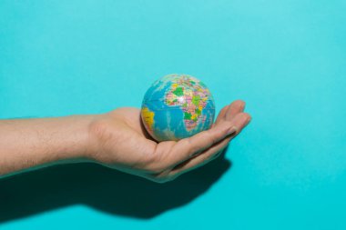 Metin için kopyalama alanı olan renkli mavi arkaplan ile dünyayı tutan top.