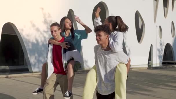 Fiatal, boldog barátok soknemzetiségű csoportja sétál az utcán, és pacsizik.. — Stock videók