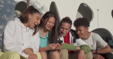 Bir grup mutlu genç arkadaş şehrin sokaklarında telefona bakıp gülüyor..