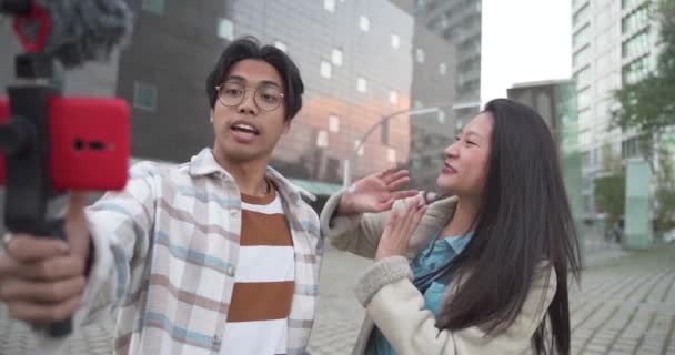Asiatique vidéo blogueurs couple regardant caméra en plein air dans la ville au ralenti. — Video