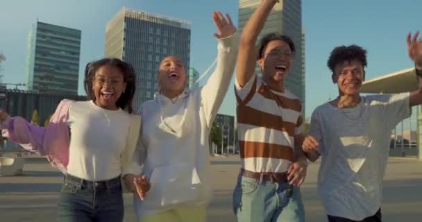 Багатоетнічна група молодих щасливих друзів біжить по вулиці, тримаючи один одного ласкаво в повільному русі . — стокове відео