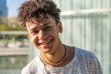 Genç, yakışıklı, Afrikalı, Amerikalı çocuk portresi güneşli bir günde kampüsteki kameraya bakıyor..