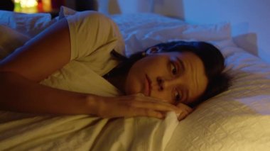 Ay 'dan gelen mavi renklerle uyumak için ışıklarını kapatan güzel bir kız. 4K yavaş çekim kırmızı kamera videosu.