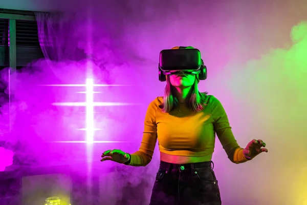 Technologie bezprzewodowe. Młoda kobieta korzystająca z okularów wirtualnej rzeczywistości w ciemnym pokoju z oświetleniem neonowym. — Zdjęcie stockowe