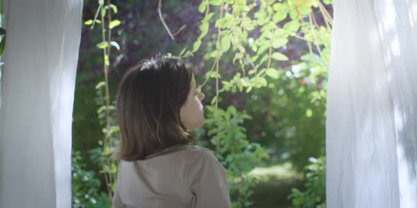 Κορίτσι κοιτάζοντας μέσα από το παράθυρο και αναπνέοντας καθαρό αέρα από την εξωτερική φύση RED κάμερα 4K. — Αρχείο Βίντεο
