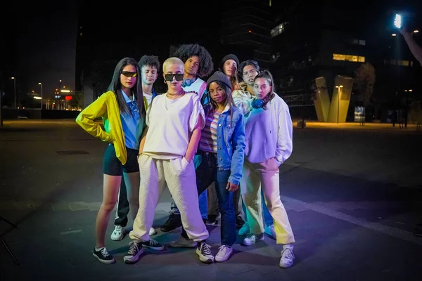 Grupo de jovens com roupas modernas na rua wth luzes de néon à noite olhando para a câmera. — Fotografia de Stock