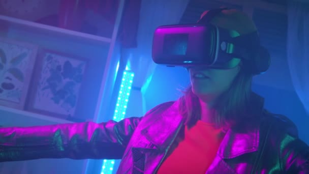 Νεαρή γυναίκα που χρησιμοποιεί γυαλιά εικονικής πραγματικότητας στο σκοτεινό δωμάτιο με νέον φωτισμό 4K αργή κίνηση RED κάμερα. Ασύρματες τεχνολογίες. — Αρχείο Βίντεο