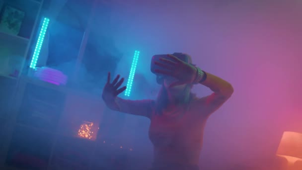 Junge Frau mit Virtual-Reality-Brille im dunklen Raum mit neonbeleuchteter 4K-Zeitlupenkamera. Drahtlose Technologien. — Stockvideo