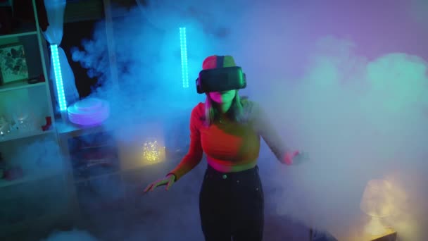 Mujer joven que usa gafas de realidad virtual en la habitación oscura con iluminación de neón 4K cámara RED de cámara lenta. Tecnologías inalámbricas. — Vídeos de Stock