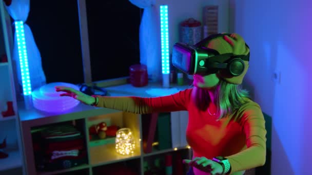 Νεαρή γυναίκα που χρησιμοποιεί γυαλιά εικονικής πραγματικότητας στο σκοτεινό δωμάτιο με νέον φωτισμό 4K αργή κίνηση RED κάμερα. Ασύρματες τεχνολογίες. — Αρχείο Βίντεο