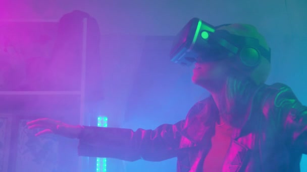 Ung kvinna med hjälp av virtual reality glasögon i det mörka rummet med neon belysning 4K slow motion RED kamera. Trådlös teknik. — Stockvideo