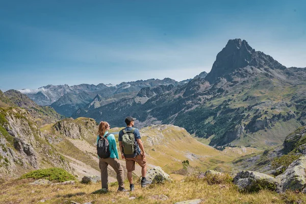 Young Attractive Couple op zoek naar het panoramische uitzicht op het prachtige berglandschap in de zomer. Ontdekking Reisbestemming en Vrijheid Concept. — Stockfoto
