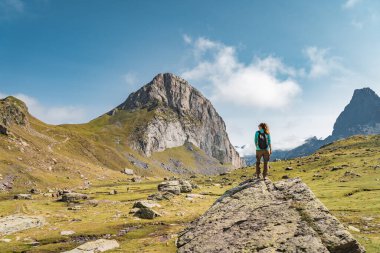 Güzel vahşi bir arazide, bir kayanın tepesinde sırt çantalı genç bir kadın. Keşif Seyahat Hedefi Konsepti