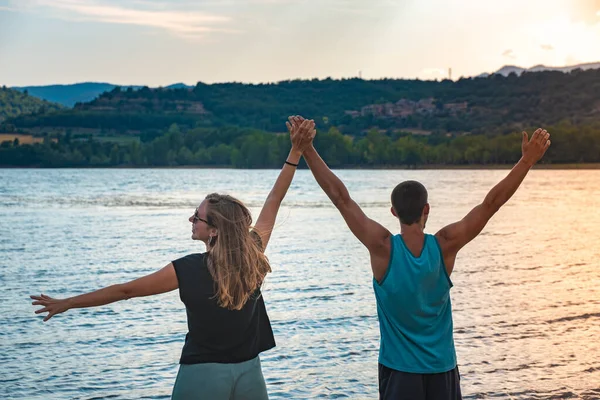 Young Attractive Couple open arms holding hands in a Beautiful Lake in summer during sunset. Discovery Travel love Destination Concept. — Fotografia de Stock