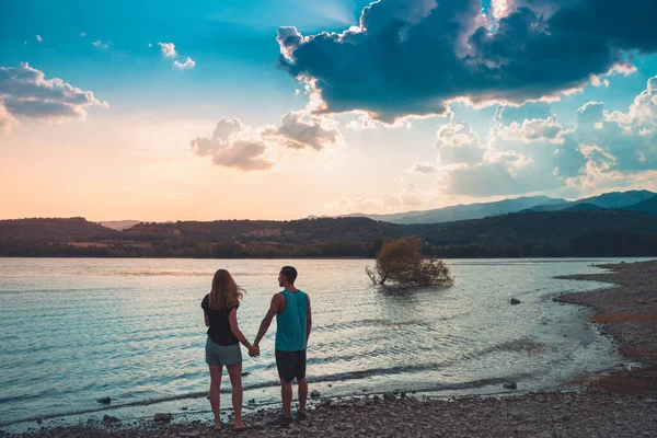 Young Attractive Couple holding hands in a Beautiful Lake in summer during sunset. Discovery Travel love Destination Concept. — Fotografia de Stock