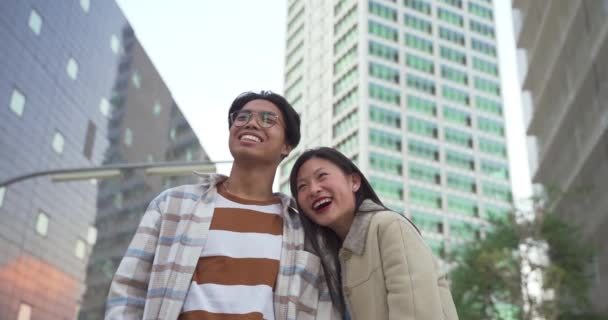 Beautiful asian couple portrait looking at camera smiling and laughing during the sunset in a modern city. — Stock Video