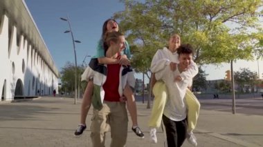 Çok ırklı, mutlu bir grup genç arkadaş gün batımında birbirlerine sevgiyle sarılarak sokakta yürüyorlar. Yüksek kaliteli video.